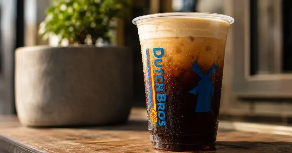 Dutch Bros Nitro Cold Brew with soft top in a clear cup showing creamy foam layer and dark coffee underneath.